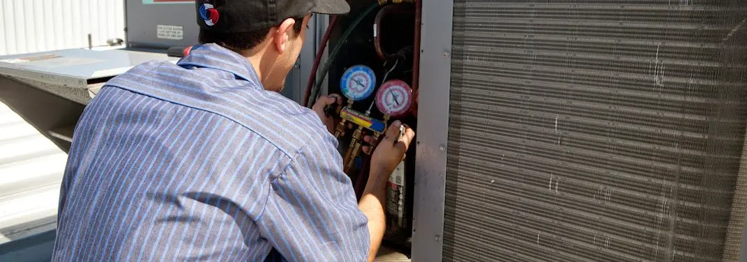 HVAC technician servicing a condenser unit in Lindon